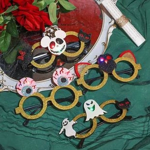Three pairs of glittery gold Halloween glasses with ghost, eye, and black cat motifs