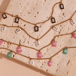 Macro detail of gold plated necklace featuring colorful enamel pendants and zircon stones