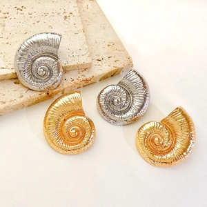 Golden and silver stainless steel ocean-themed seashell spiral earrings on marble