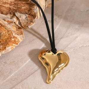 Macro shot of gold-plated irregular lava heart pendant on minimalist black cord necklace