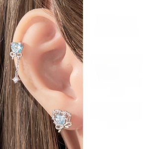 Detail of silver bow earrings with heart-shaped light blue zircon in a layered design