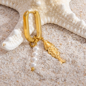 Detail of gold U-shaped earring with fish charm and white pearls on white starfish background