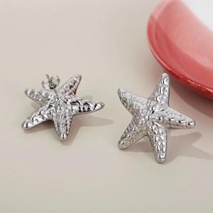 Macro detail of silver starfish stud earrings showing textured surface and butterfly back