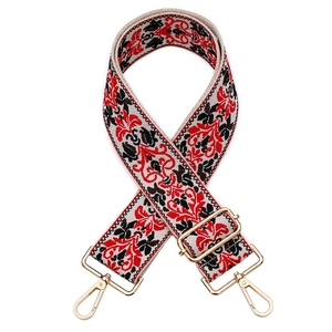 Close-up of ethnic floral jacquard bag strap with gold metal buckles on white background