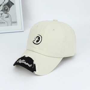 Detail of 3D embroidered letter D and cursive text on a vintage beige baseball cap