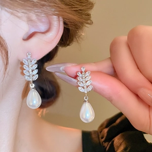 Elegant silver wheat ear pearl drop earrings with zircon crystals worn by a model