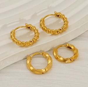 Macro detail of gold plated croissant and twisted rope hoop earrings on white tray