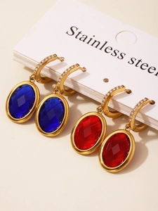 Detailed macro of stainless steel gold earrings with blue and red multifaceted glass stones