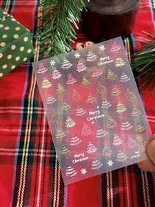Macro detail of Christmas tree and snowflake nail stickers in gold and pink hues