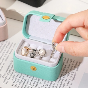 Close-up of mint green portable jewelry box showing ring slots and soft velvet interior