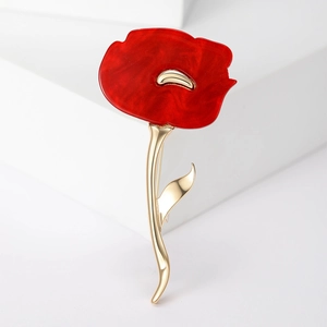 Detail of a red enamel poppy flower brooch with golden stem on white background