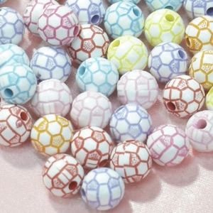 Gros plan de perles de football en acrylique colorées pour bijoux sur tissu rose