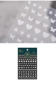Detail of 3D nail art stickers with white stars, butterflies and hearts pattern