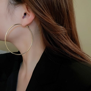 Close-up of a model wearing large minimalist golden hoop earrings with a metallic finish