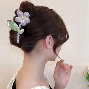 Détail d'une pince à cheveux fleurie avec pétales en émail rose et strass brillants