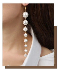 Detail of long drop earrings featuring eight graduated faux pearls with gold plated hooks