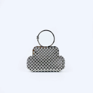 Detail of silver beaded handbag with round metal handle and shimmering woven texture
