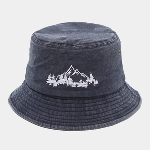 Détail de la broderie de montagne et œillets en cuivre sur bob en denim délavé
