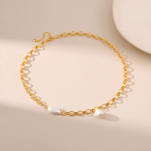Detail of gold chain necklace with irregular white pearls and lobster clasp on beige background