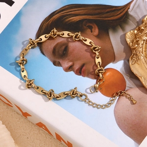 Detail of gold coffee bean link anklet with lobster clasp on a fashion magazine