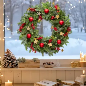 Christmas pine needle wreath with red berries and gold stars on glass window