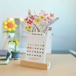 Detail of wooden desk calendar with bloomy flowers and February view on paper