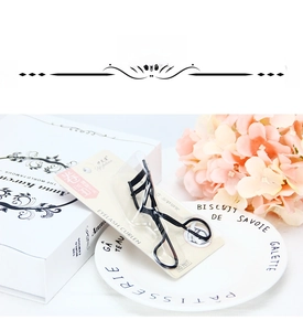 Close-up of a professional black metal eyelash curler on a decorative porcelain plate