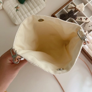 Interior view of beige quilted bag featuring magnetic snap closure and silver hardware
