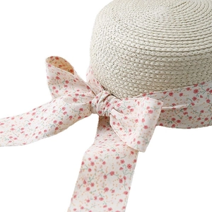 Women's summer straw sun hat with floral bow ribbon decoration on white background