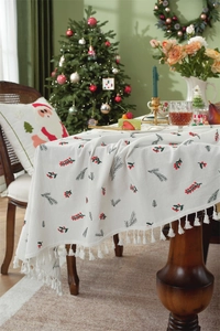 Close-up of festive red berries embroidery and white tassel fringe on cotton tablecloth