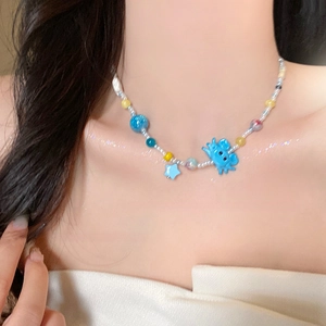 Gros plan du collier de perles avec pendentifs étoile et crabe bleus sur un mannequin
