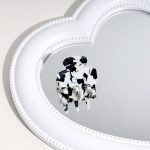 Black and white marble hair claw clip reflecting on a heart-shaped mirror detail