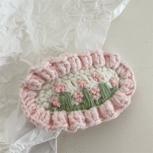 Close-up of handmade crochet flower hair clip with pink ruffled edges and floral embroidery