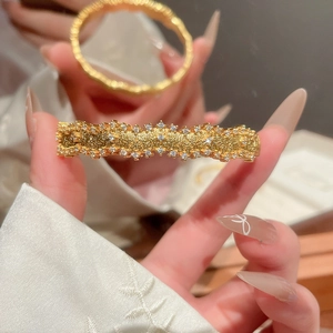 Detailed macro view of gold-plated hair clip featuring matte texture and sparkling rhinestones