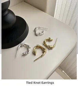Detail view of twisted knot stud earrings in polished gold and silver finishes