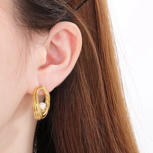 Detailed view of a gold-finish textured hoop earring with a central white pearl inlay