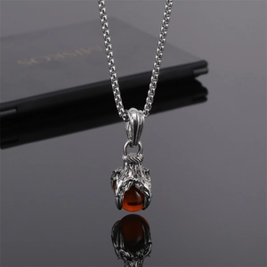 Gros plan d'un pendentif griffe de dragon punk avec perle ambre et chaîne élégante