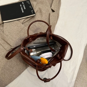 Brown pleated dumpling tote bag with drawstring top shown with daily essentials
