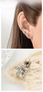 Macro shot of silver daisy stud earrings with blue rhinestones and screw-back detail