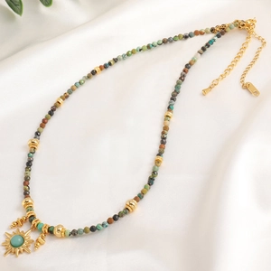 Bohemian beaded necklace with turquoise stones and gold sun pendant on white silk