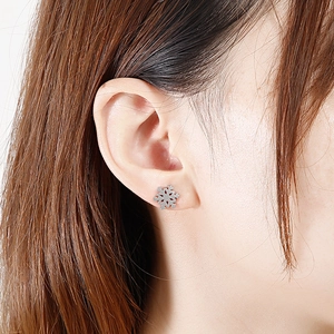 Close-up of a model wearing silver snowflake stud earrings made of stainless steel