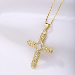 Macro detail of gold-plated hollow cross pendant featuring sparkling zircon gemstones