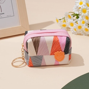 Detail of mini coin purse with geometric patterns, pink zipper, and strawberry charm