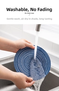 Washable deep blue round woven placemat being rinsed under a water faucet