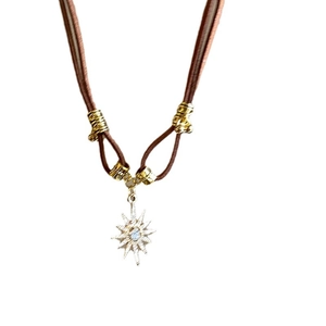 Brown leather cord necklace featuring a gold starburst pendant with a clear center crystal