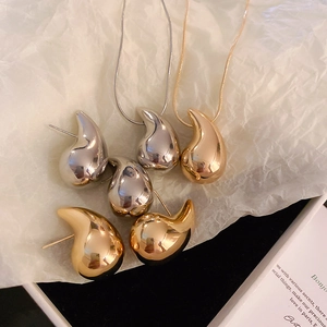 Chic gold and silver waterdrop earrings and necklaces on white paper in a black box