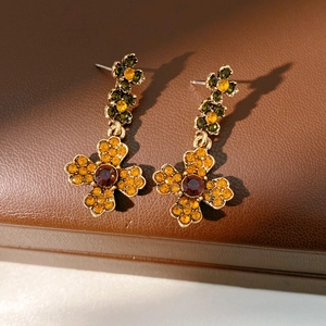 Vue macro de boucles d'oreilles fleur vintage dorées avec strass orange et rouge