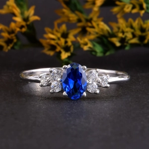 Elegante zilveren ring met ovale blauwe saffier en zirkonen op een donkere stenen basis