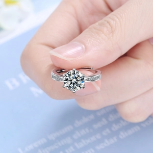 Elegant silver ring with a six-prong round zircon and small side stones held by a hand