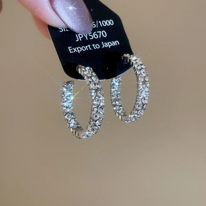 Macro detail of S925 sterling silver C-shaped hoop earrings with sparkling pavé zircons